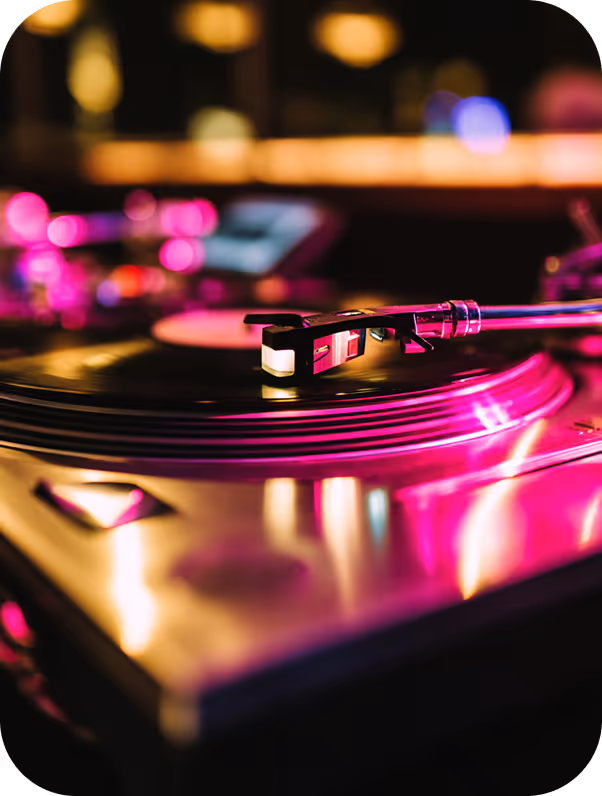 Close-up of a vinyl record player with colorful pink and purple lighting.