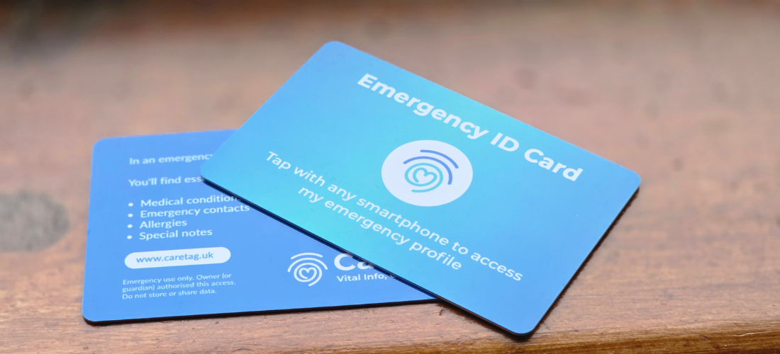 CareTag emergency ID kit showing a black NFC-enabled wristband and blue emergency ID card resting on a smartphone, used to access vital medical information in emergencies.