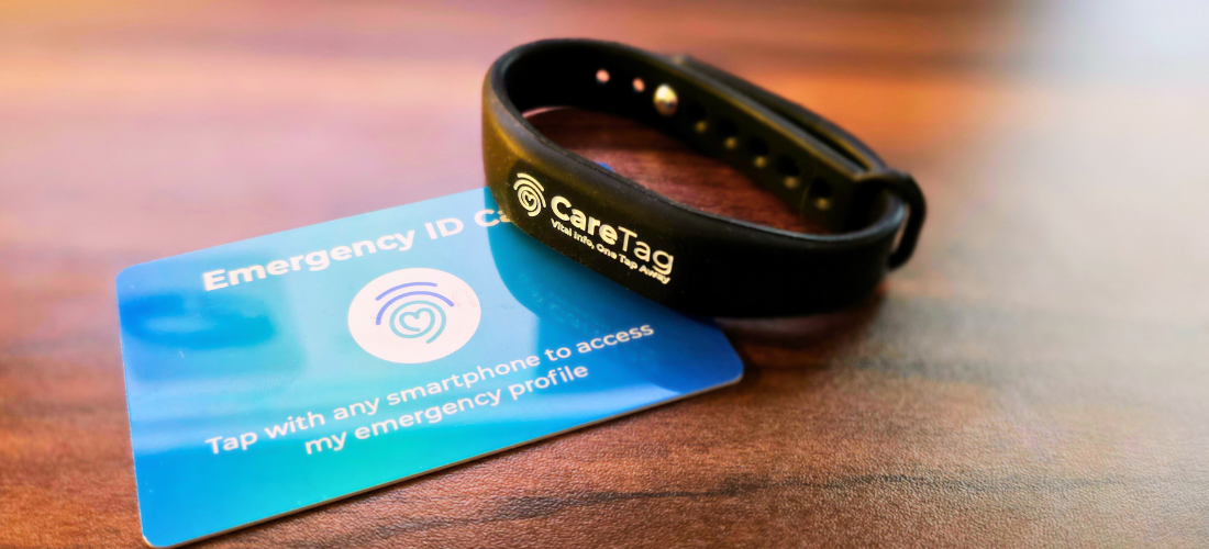 CareTag emergency ID kit showing a black NFC-enabled wristband and blue emergency ID card resting on a smartphone, used to access vital medical information in emergencies.