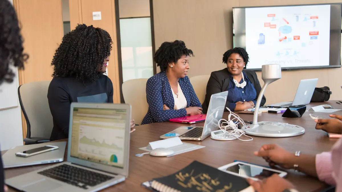 Supply chain compliance discussion during a meeting with laptops and a presentation on company threats