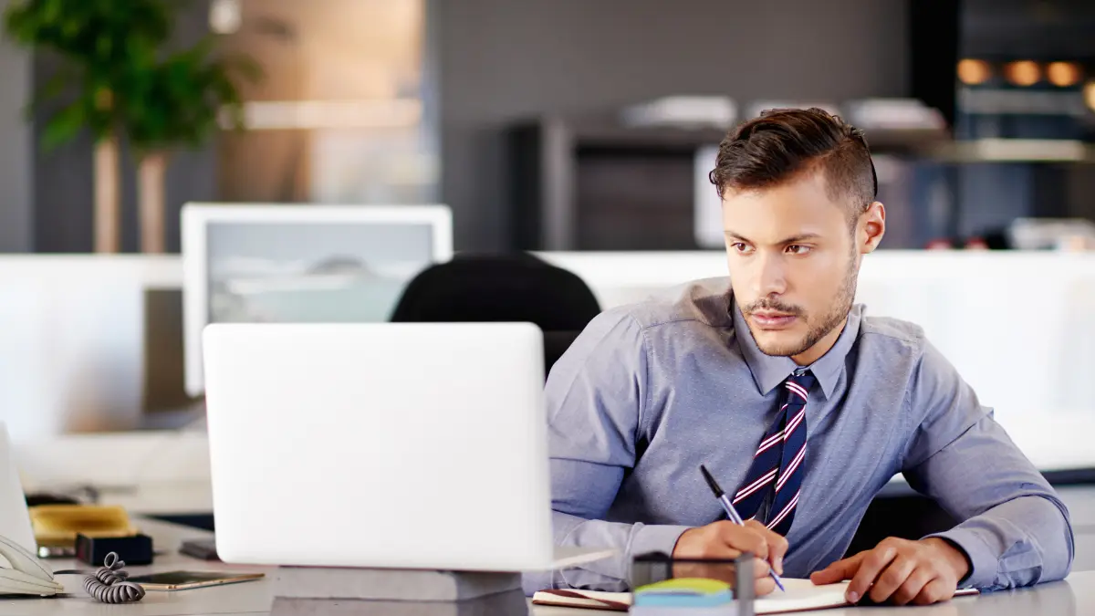 A businessman working on a laptop in a bright office, representing global compliance due diligence processes