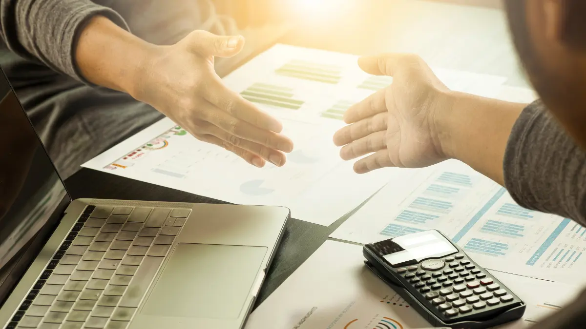 Business professionals shaking hands over financial documents, symbolizing a data-driven supplier onboarding process.