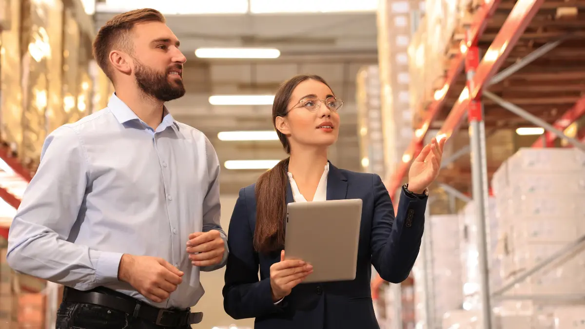 Vendor risk management benefits illustrated by business professionals evaluating supplier performance in a warehouse.