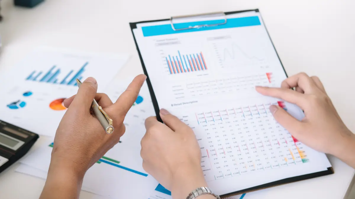 Vendor risk management review with hands pointing at performance metrics on a data report.