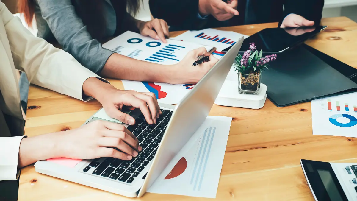 Vendor compliance management meeting with professionals analyzing business reports and charts.