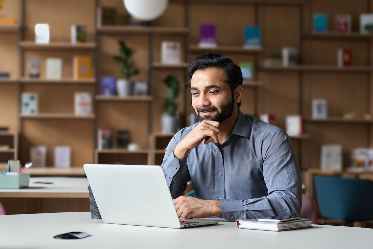 Entrepreneur smiling while reading something from his laptop