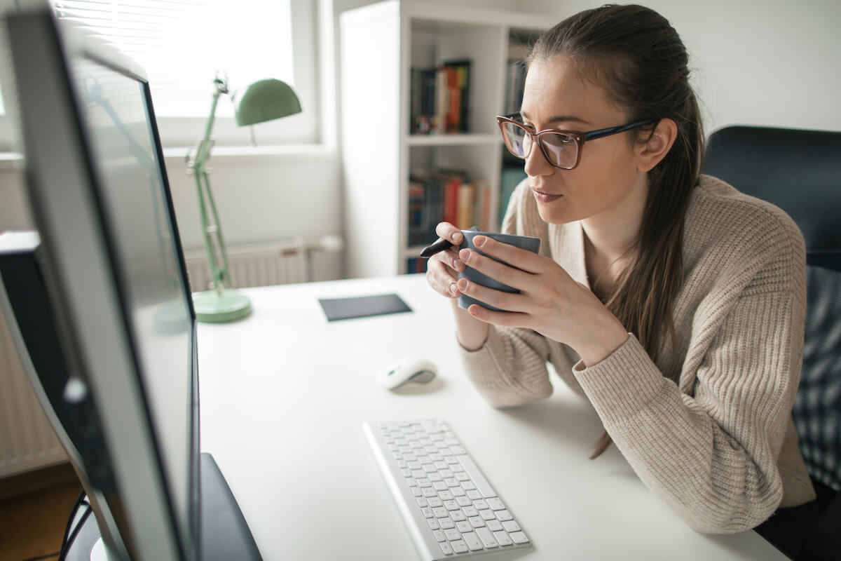 Supplier onboarding: entrepreneur holding a cup of coffee and looking at a computer