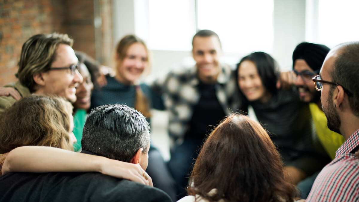 A smiling team of coworkers gather in a huddle