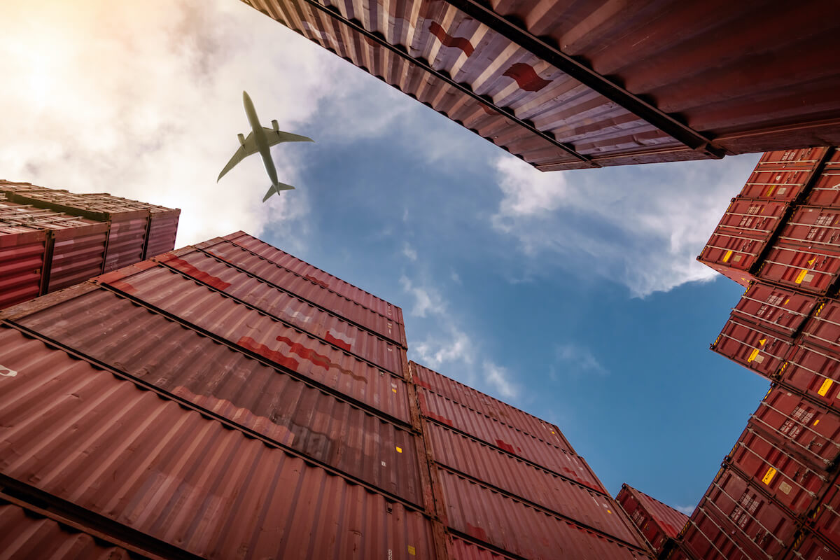 Supply chain resilience: An airplane flies above stacks of shipping containers