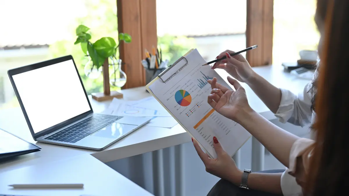 Risk and compliance integration discussed while reviewing financial analytics on a clipboard.