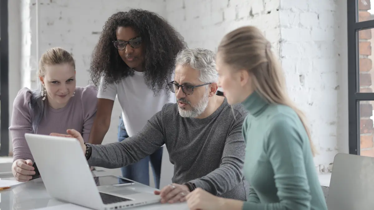 Supplier monitoring program team reviewing data together on a laptop in a bright, collaborative workspace.