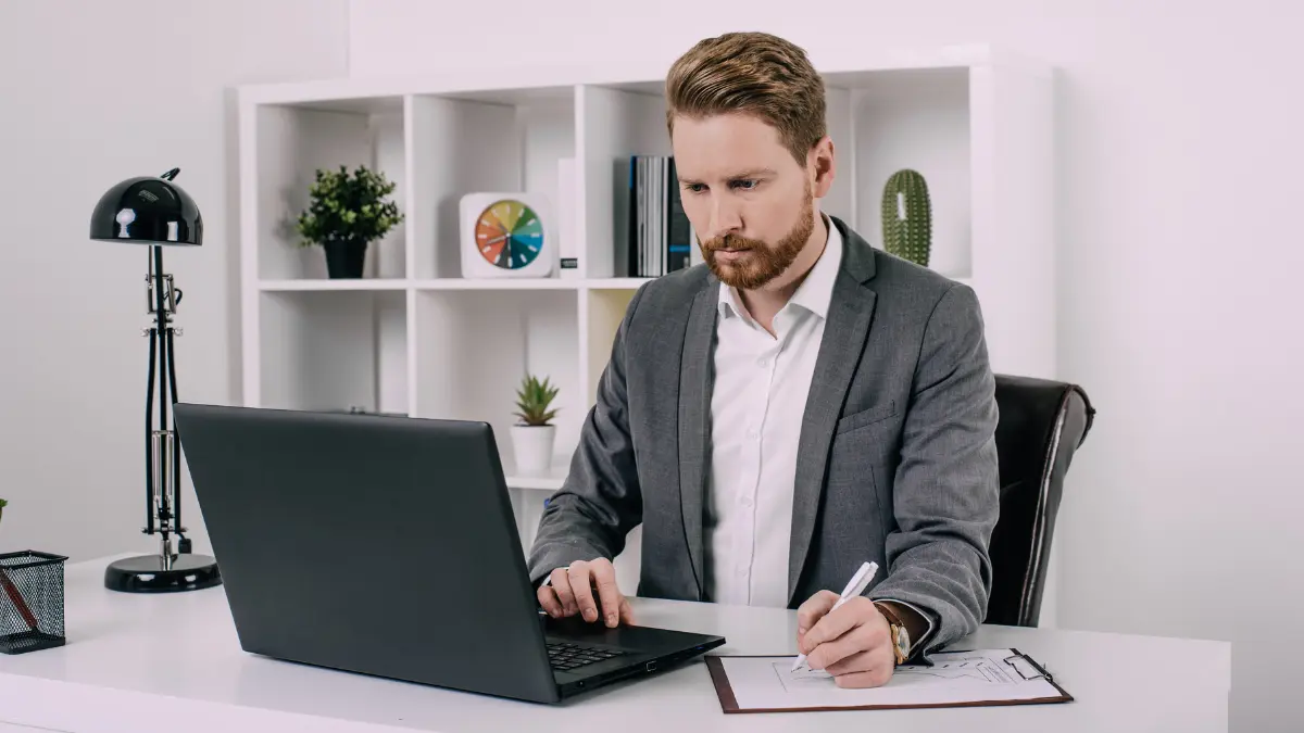 Supply chain risk management software team collaborating on laptops and tablets in a well-lit office.