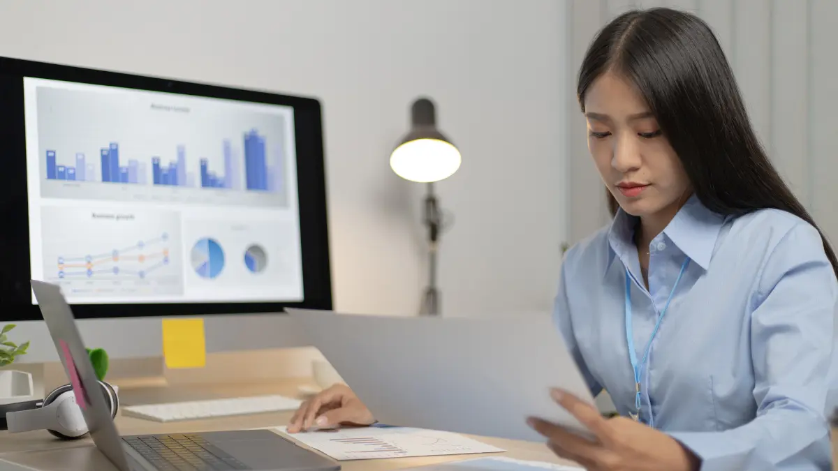 Third-party risk management software displayed on a laptop while professionals analyze data and reports together.