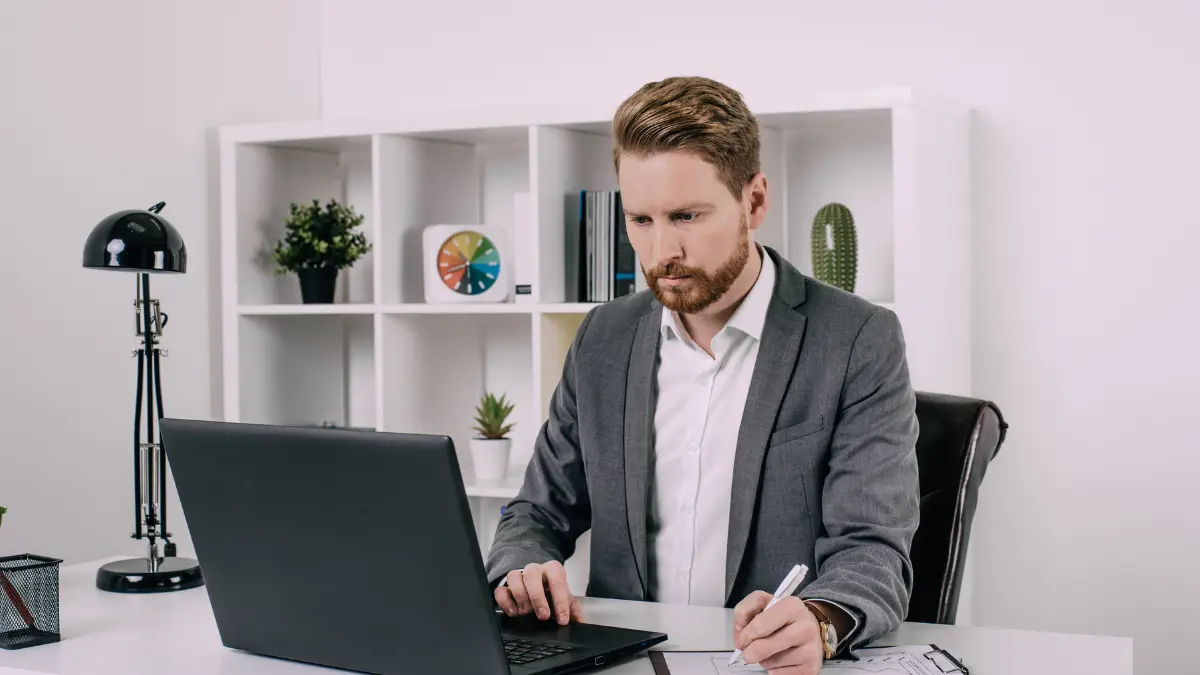 ESG risk management professional analyzing data on a laptop at a modern office desk.