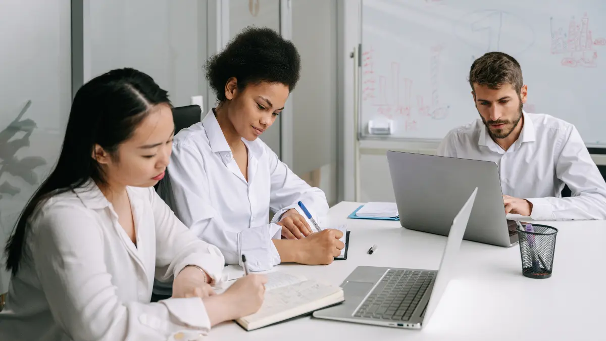 Scope 3 emissions reporting discussed by a diverse team collaborating with laptops and notes in a meeting room.