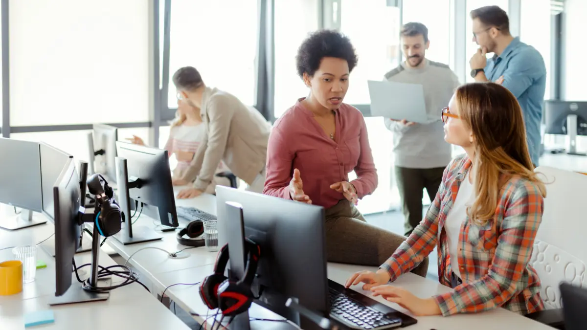 Automated risk management tools being discussed by a team of professionals collaborating around desktop computers in an open office