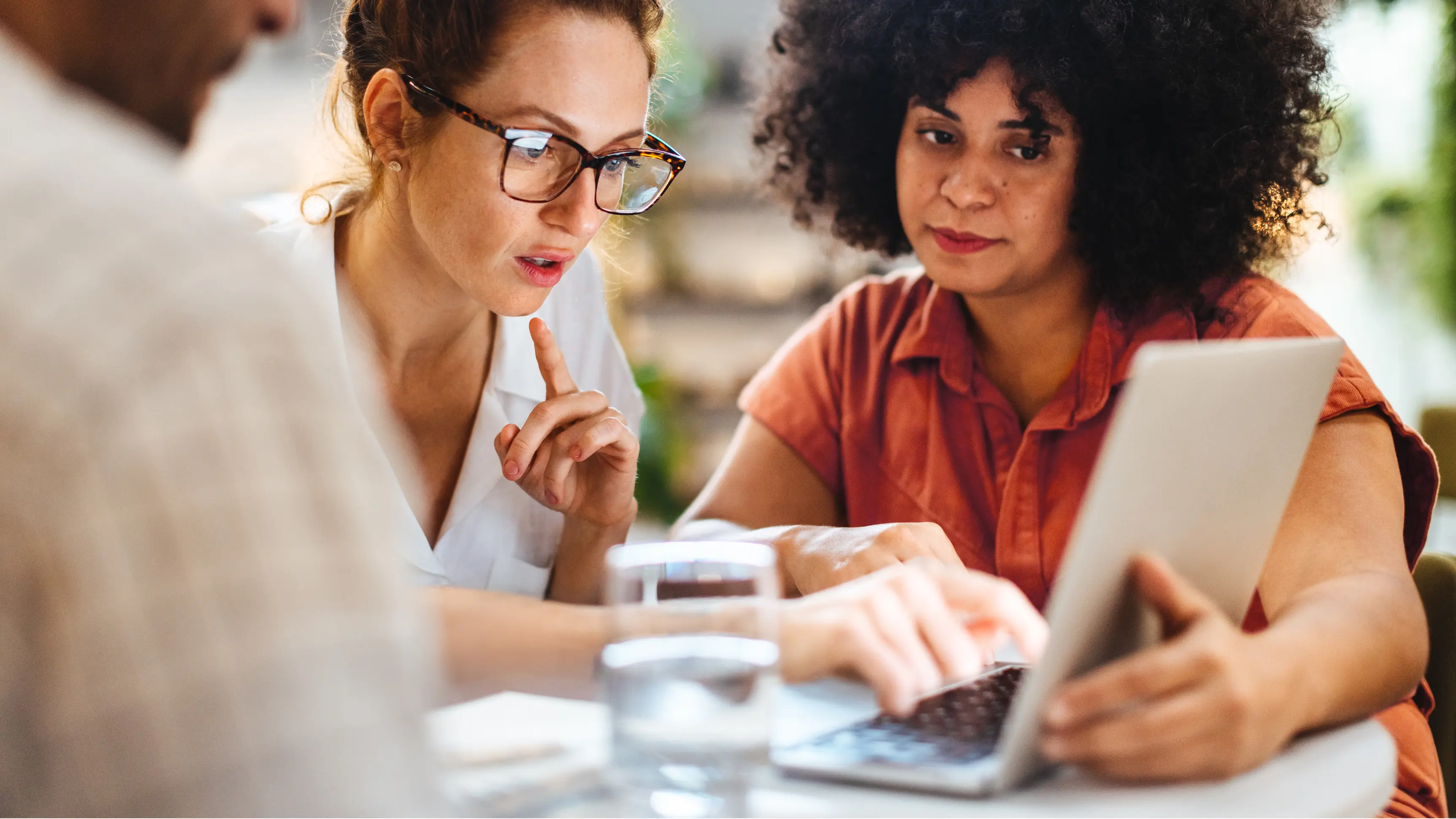 Third-party risk monitoring in action as two professional women collaborate over a laptop and tablet during a business meeting