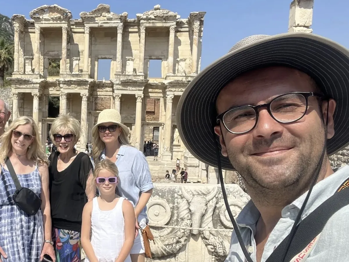 Family Close-Up at Celsus Library in Ephesus A smiling family takes a close-up selfie in front of the historic Celsus Library ruins in Ephesus on a bright, sunny sightseeing day in Turkey.