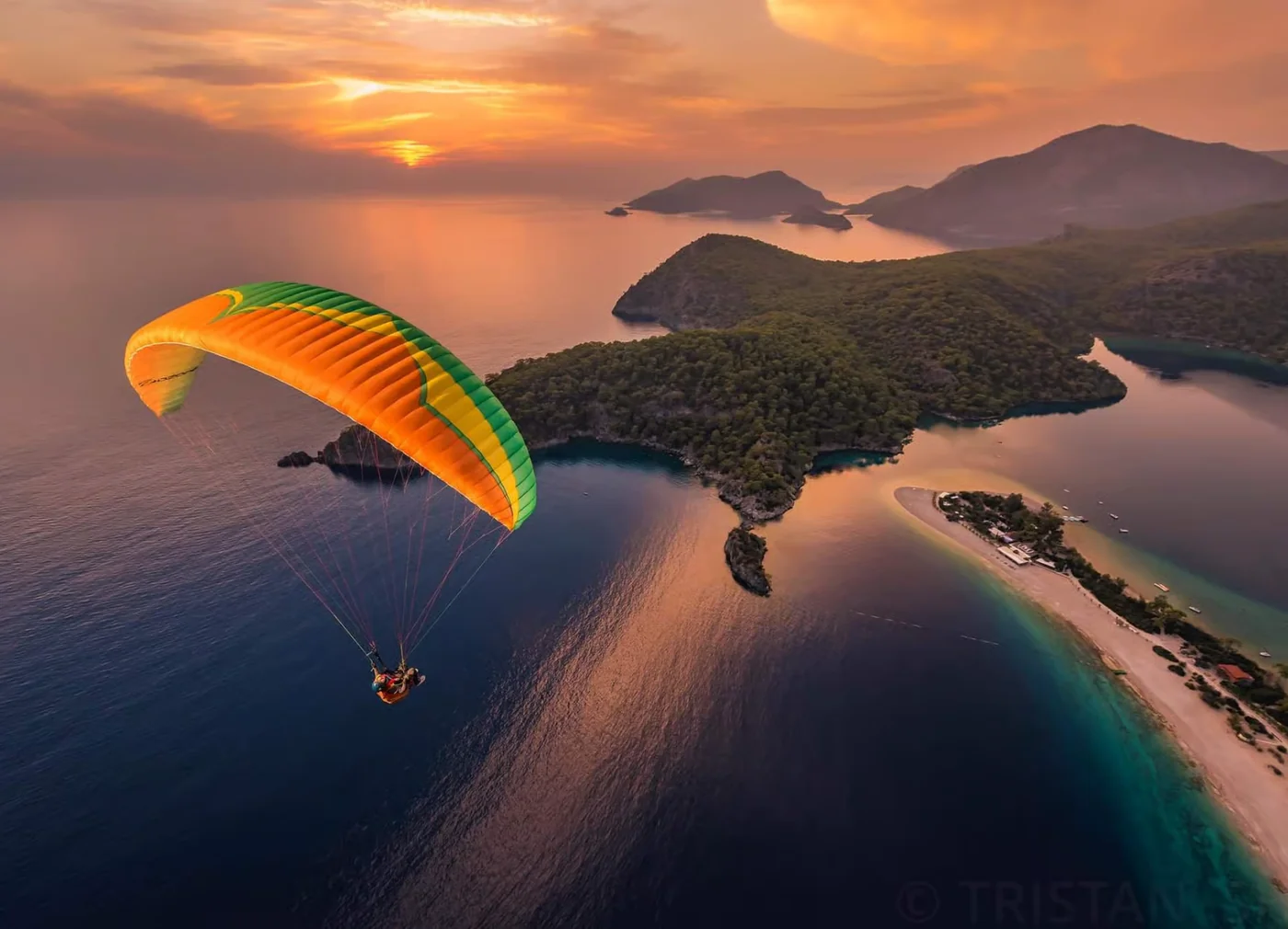 Paragliding over Ölüdeniz Blue Lagoon at sunset from Babadağ Mountain. Experience one of the most iconic aerial views on the Lycian Coast in Turkey.