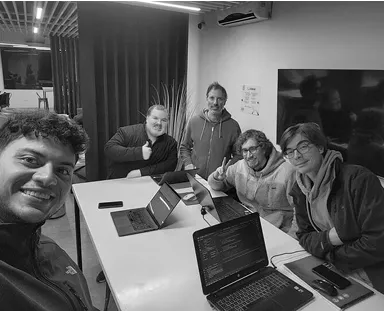 A group of people sitting around a table with laptops.