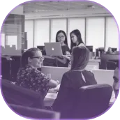 A group of women sitting around a table with laptops.