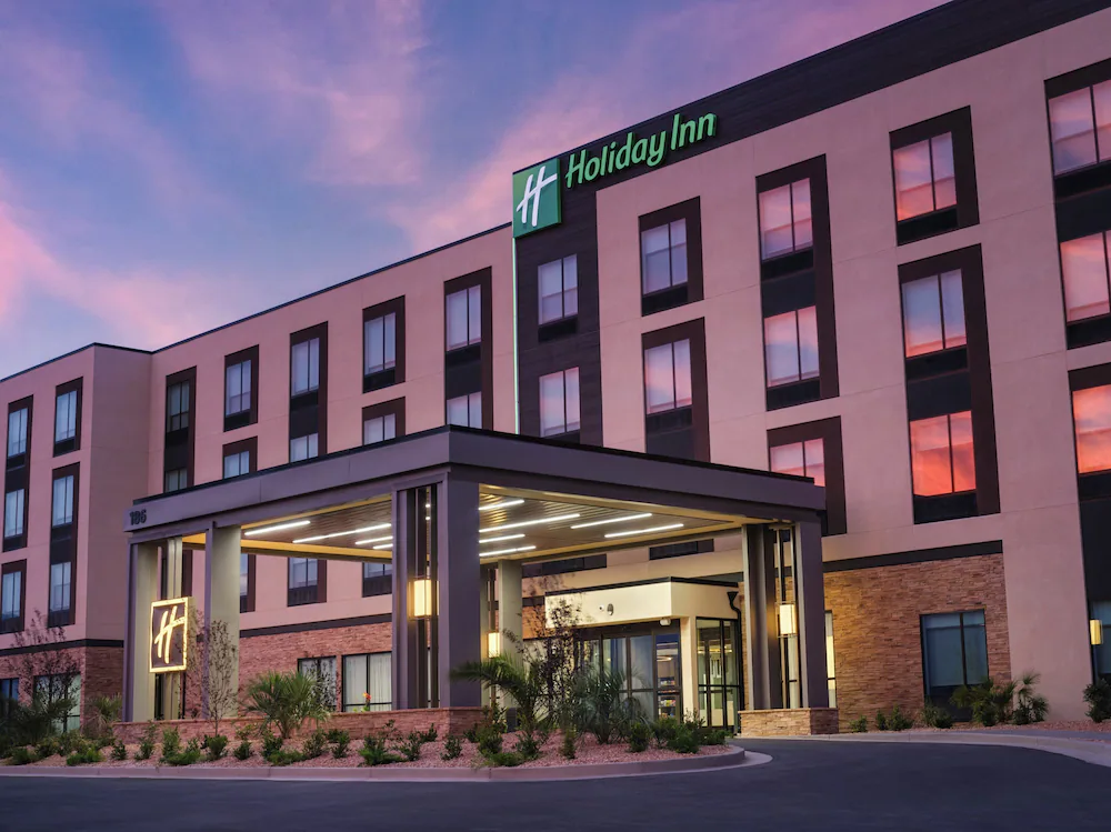 Exterior view of a Courtyard by Marriott hotel building at sunset with illuminated entrance canopy and landscaped surroundings.
