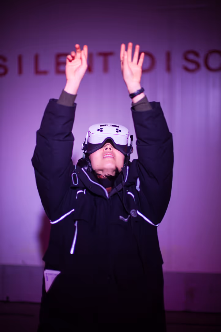 Een vrouw steekt haar handen hoog in de lucht terwijl ze in vr is.