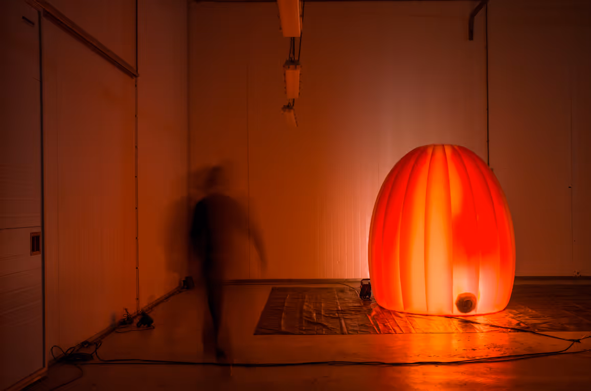 Red illuminated inflatable cocoon from The Oxytocine Machine VR art installation with participant at Katoenhuis Rotterdam