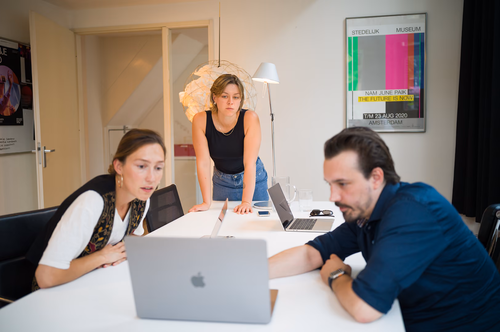 Drie teamleden van Studio Vrij bekijken samen werk op een laptop