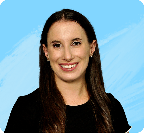 Smiling woman with long brown hair wearing a black top against a light blue background.