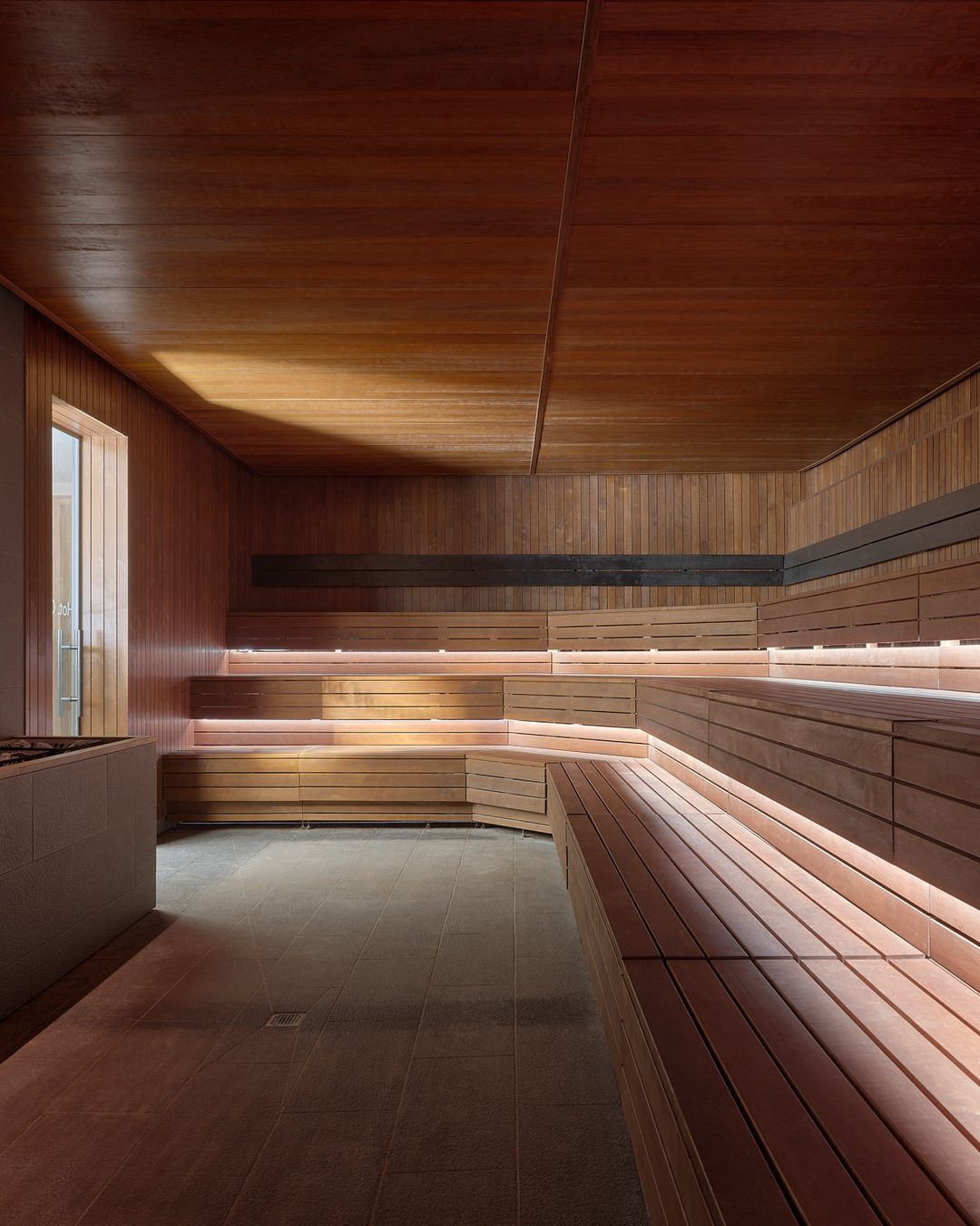 Finnish sauna interior at Lore Bathing Club with cedar wood benches and warm ambient lighting