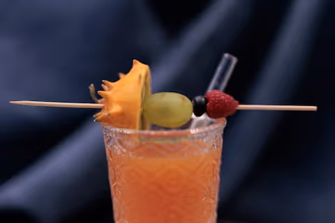 Succo di frutta arancione in bicchiere con guarnizione di frutta.