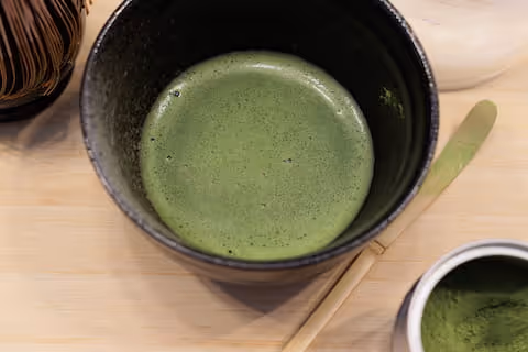 Tè matcha verde in una ciotola scura.