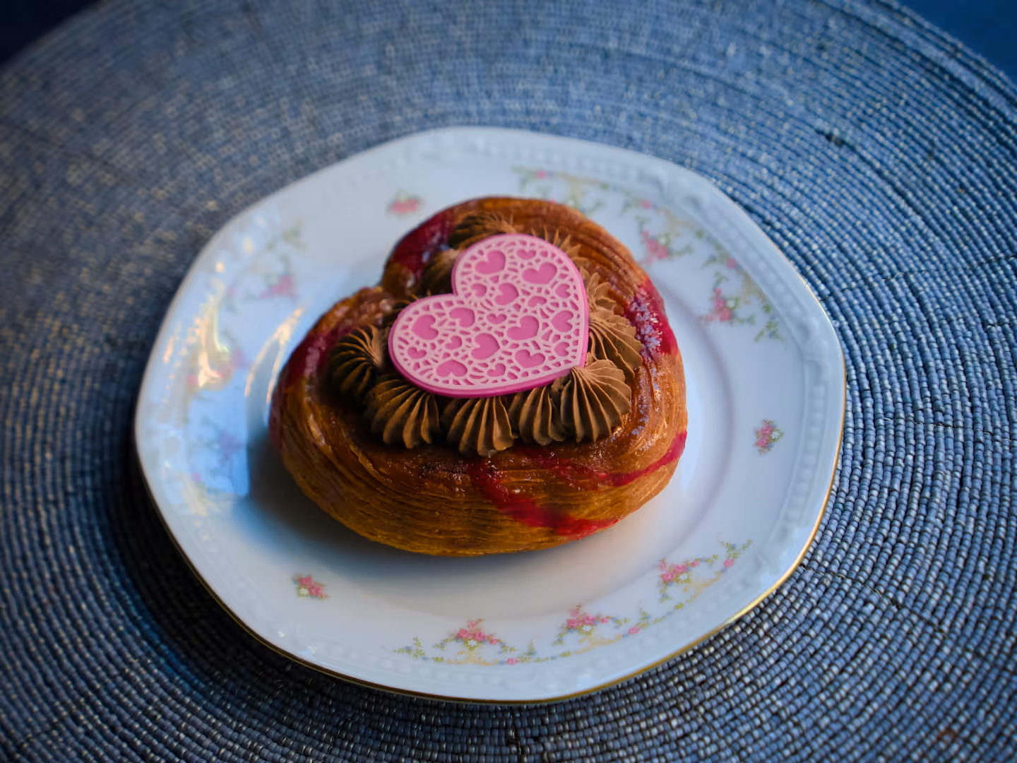 Viennoiserie a forma di cuore farcita al cioccolato, con decorazione rosa a forma di cuore.