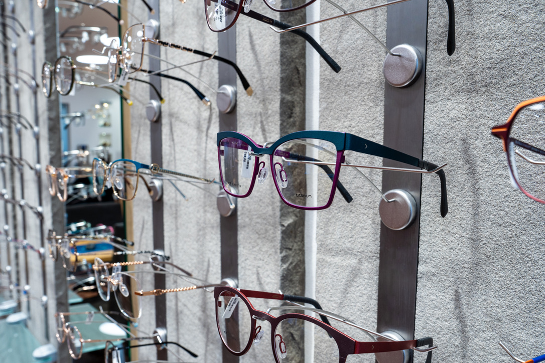 Auswahl unterschiedlicher Brillenfassungen an einer Wand im Optikgeschäft