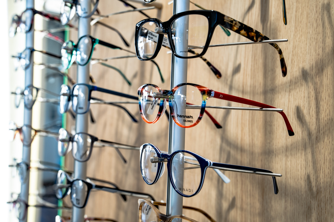 Verschiedene farbige Brillenfassungen auf einem Präsentationsständer bei Die Brille Dömer.