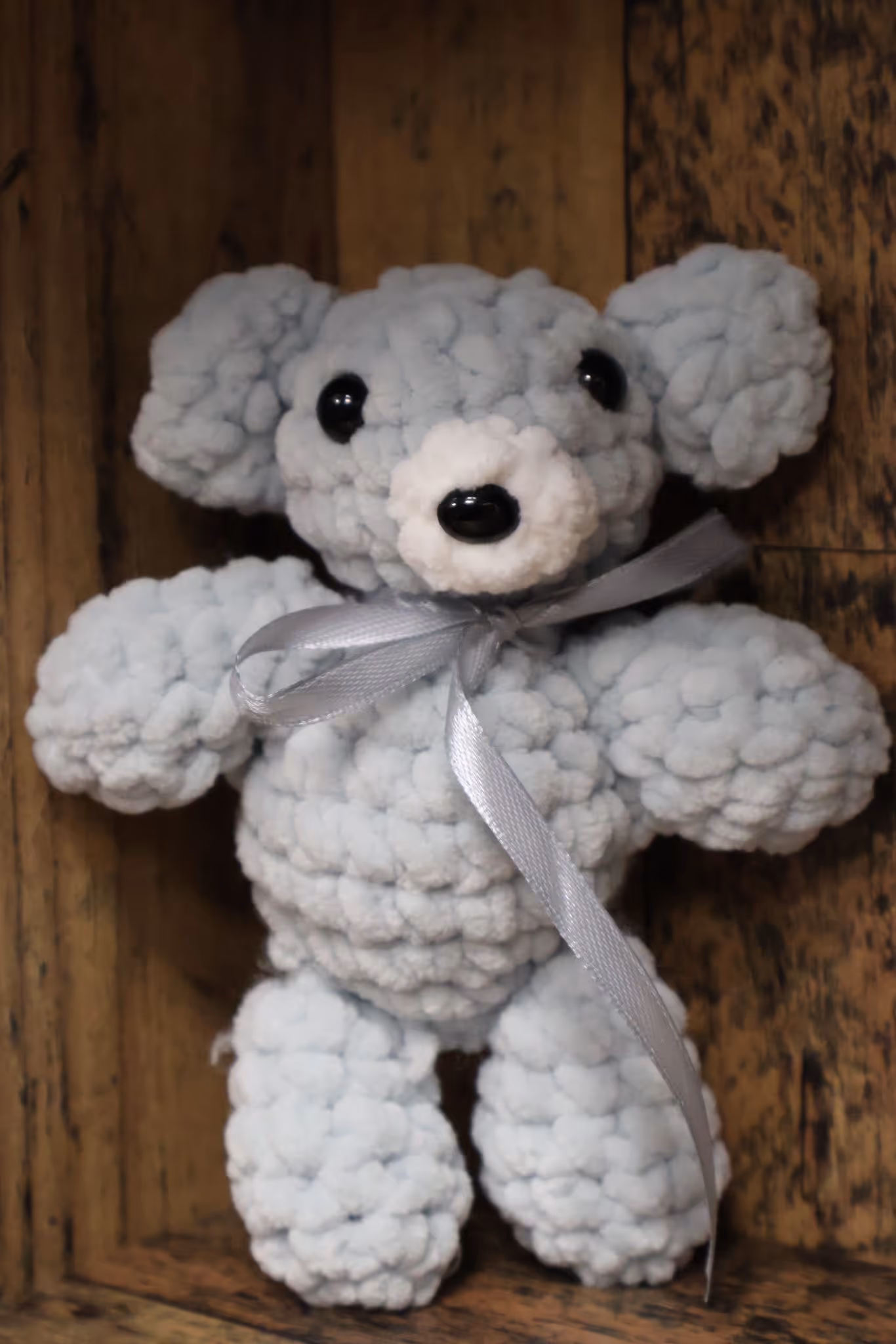 Jasnoniebieski szydełkowany miś z szarą wstążką – ręcznie wykonany brelok.