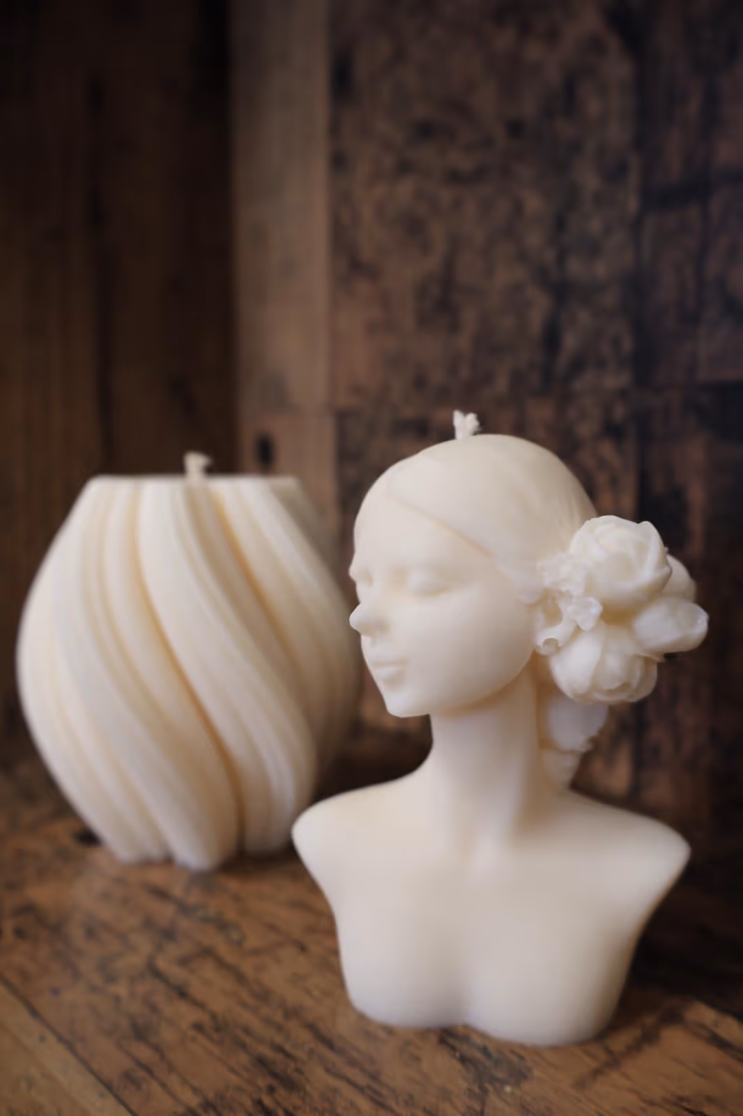 Artystyczna świeca w kształcie popiersia kobiety z białym kwiatem.