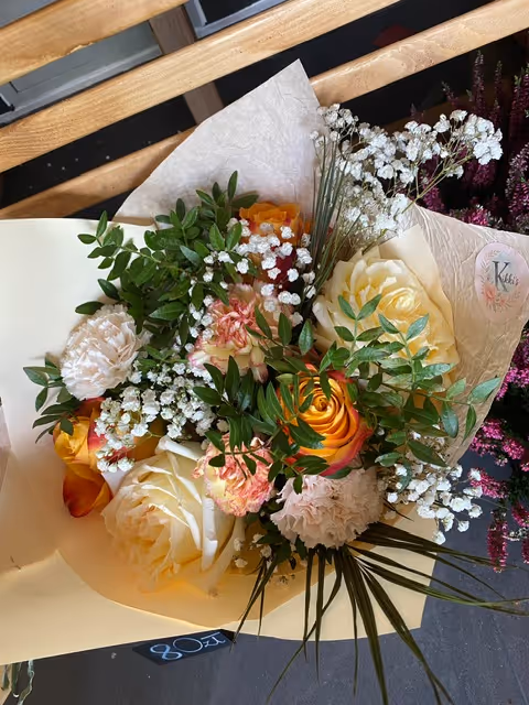 Energetyczny bukiet z żółtymi, różowymi i pomarańczowymi różami oraz zielenią.