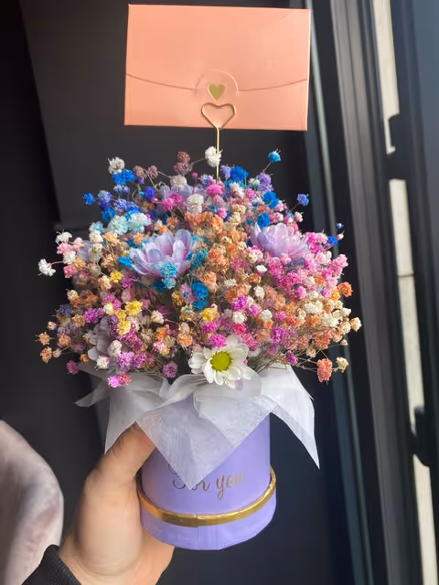 Kolorowa gipsówka w stylu tęczowym, ułożona w ozdobnym fioletowym pudełku.