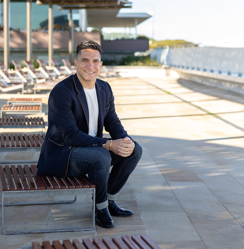 Chris Tonich, Perth real estate agent, smiling in a suit at City Beach