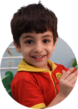 Smiling young boy with short dark hair wearing a red and yellow shirt.