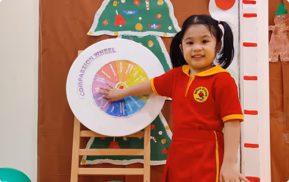 A female teacher and a young girl in red uniforms sitting at a table with colorful educational tools in a classroom.