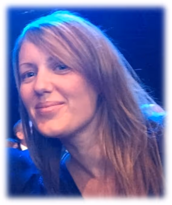 Close-up of a woman with long light brown hair smiling slightly against a blurred blue background.