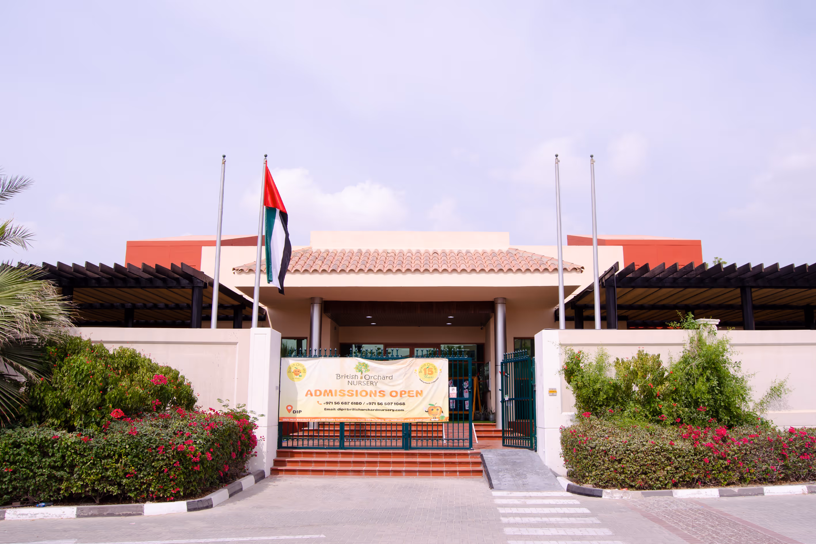 Entrance of British Orchard Nursery with open gate, banner stating admissions open, and a UAE flag.