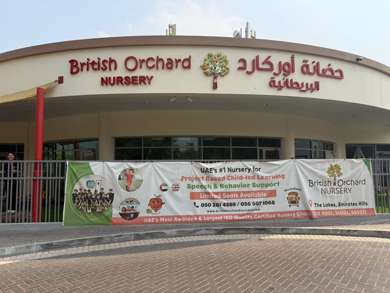 Front view of British Orchard Nursery building with a large banner advertising project-based child-led learning, speech and behavior support, and contact information.