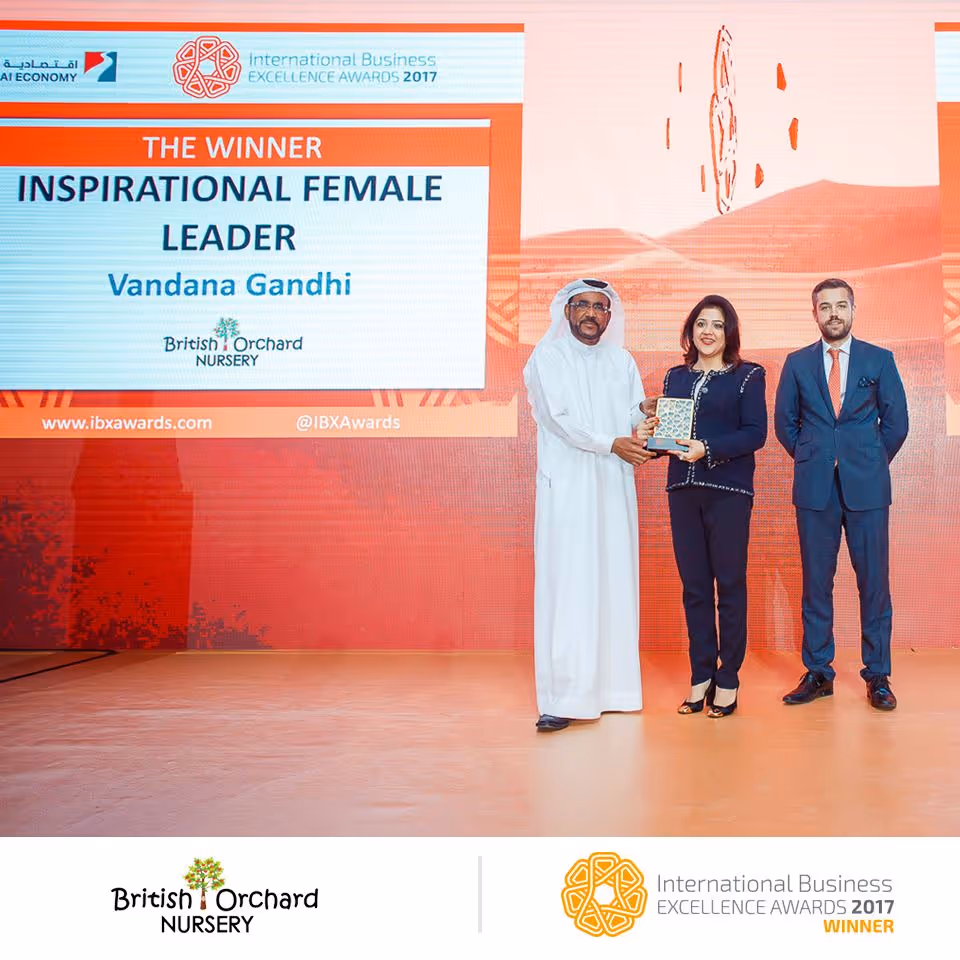 Vandana Gandhi receiving the Inspirational Female Leader award at the International Business Excellence Awards 2017, standing between two men on stage.