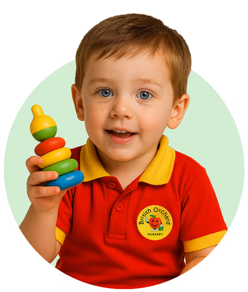Young boy in a red British Orchard Nursery shirt holding a colorful stacking toy.
