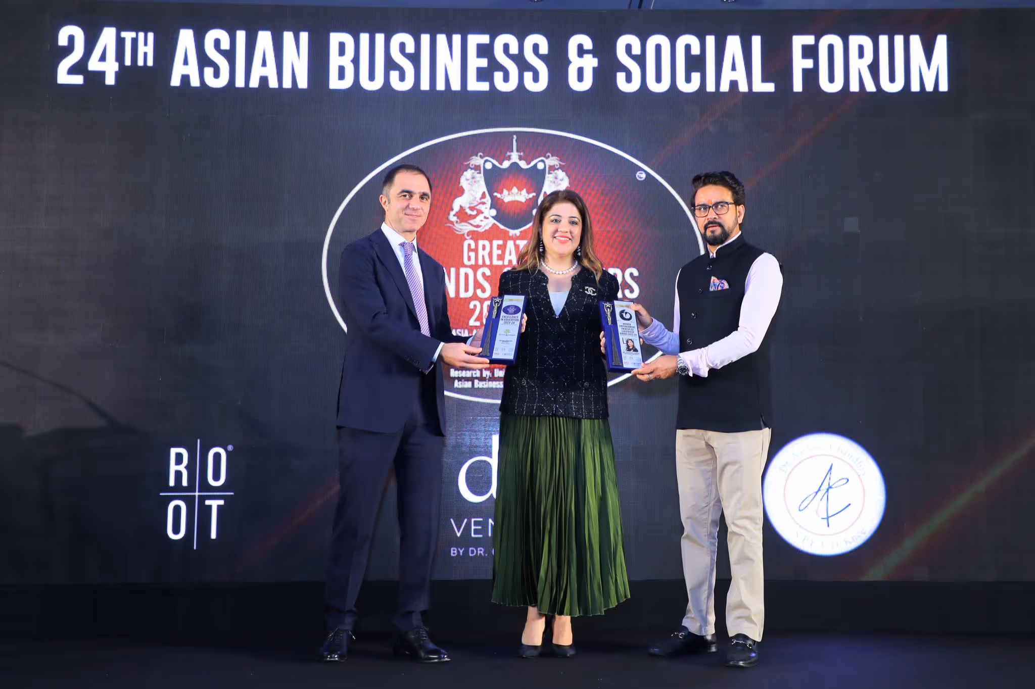 Three people standing on stage at the 24th Asian Business & Social Forum holding awards.