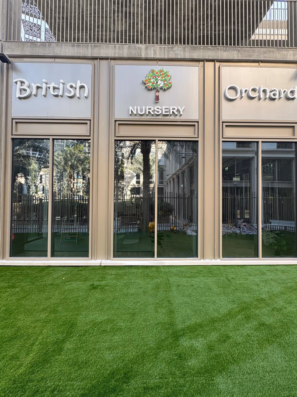 Facade of a nursery with large glass windows, a tree logo, and the words 'British Nursery Orchard' above.